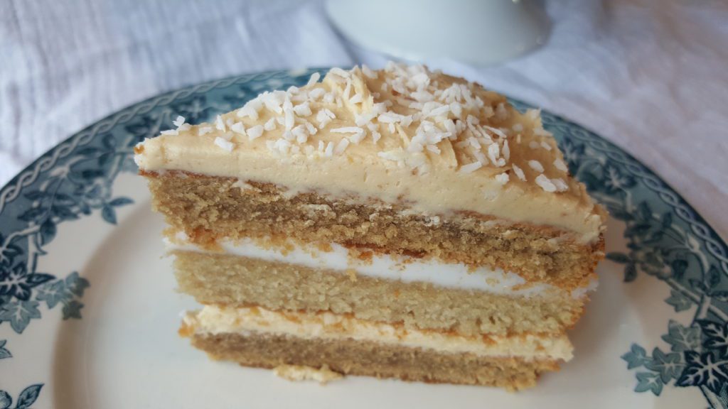 Coconut coffee cake slice with coffee buttercream icing and coconut icing and coconut flakes on top