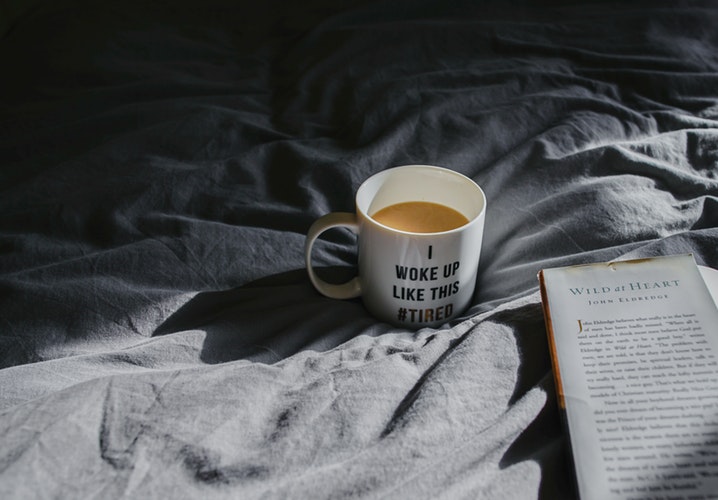 Tired mug of coffee on bed