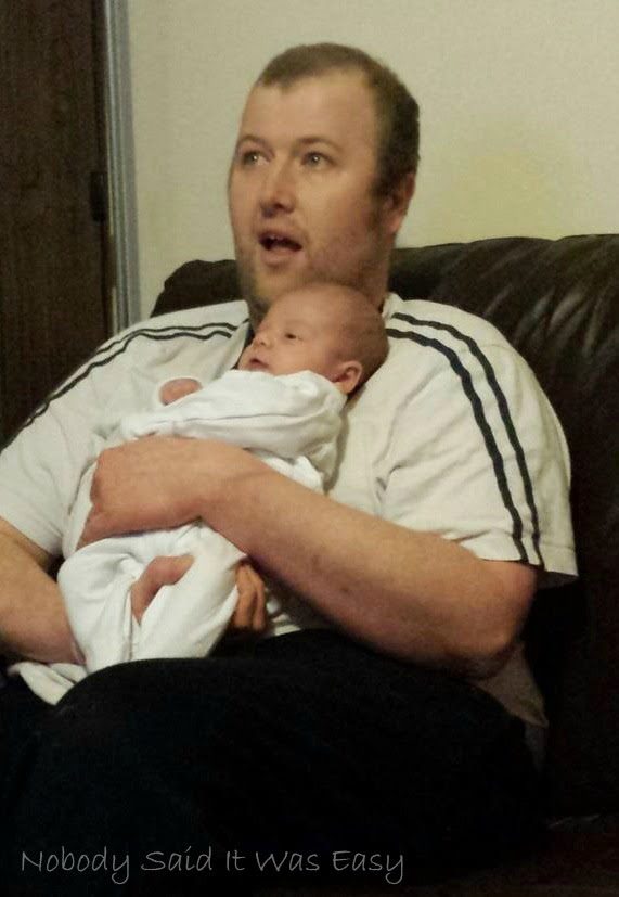 A man holding a baby while looking ahead