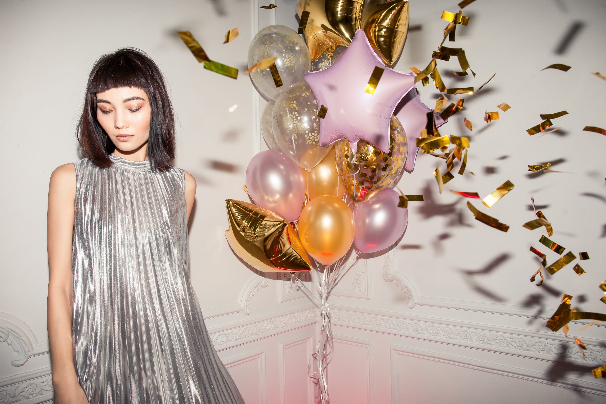 woman in grey party dress stood next to a bunch of balloons; Planning For The Post-Covid Party Of Your Dreams