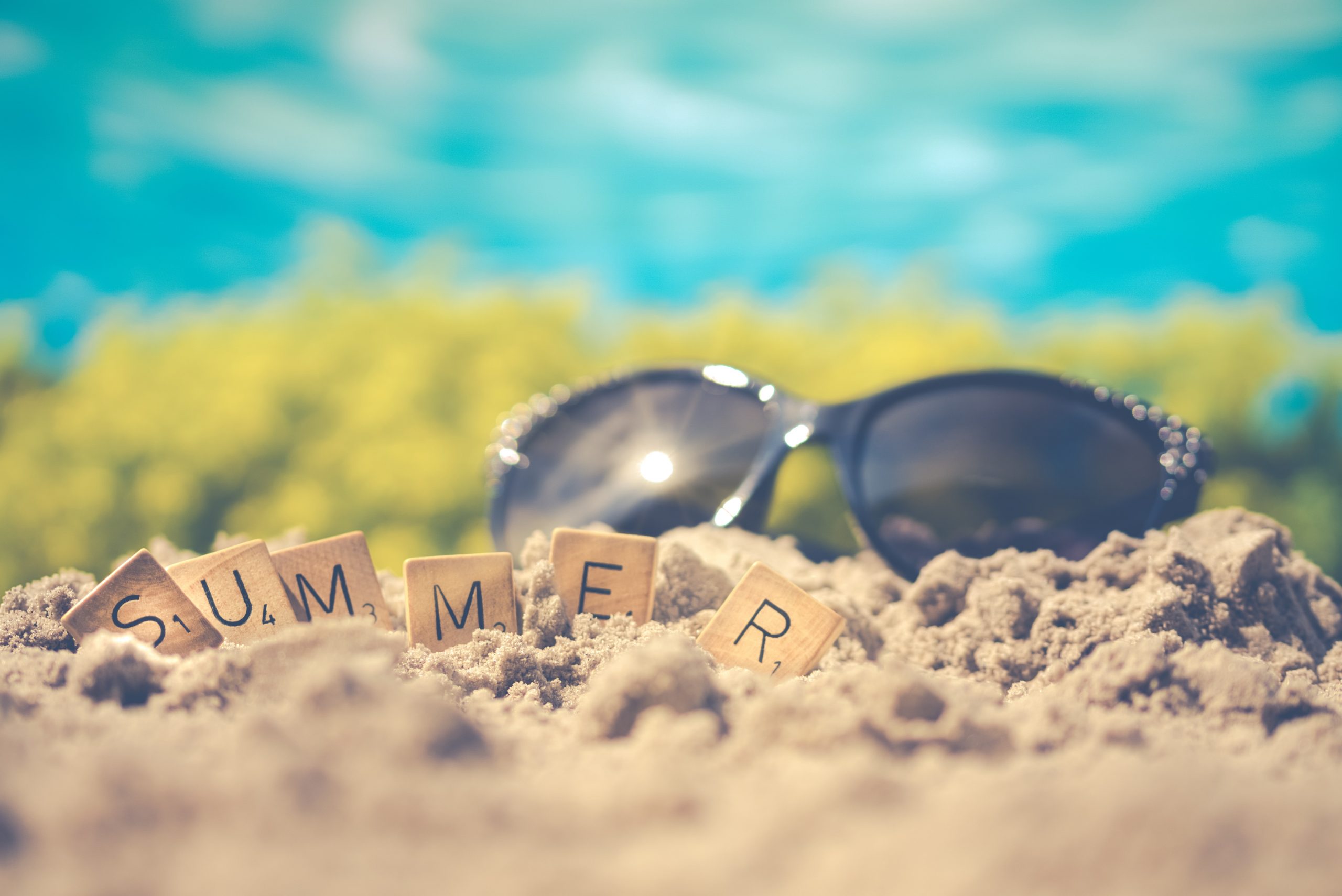 "Summer" written out in scrabble letters in front of black sunglasses on the sand; 3 Ways to Keep Your Home Cool in the Summer