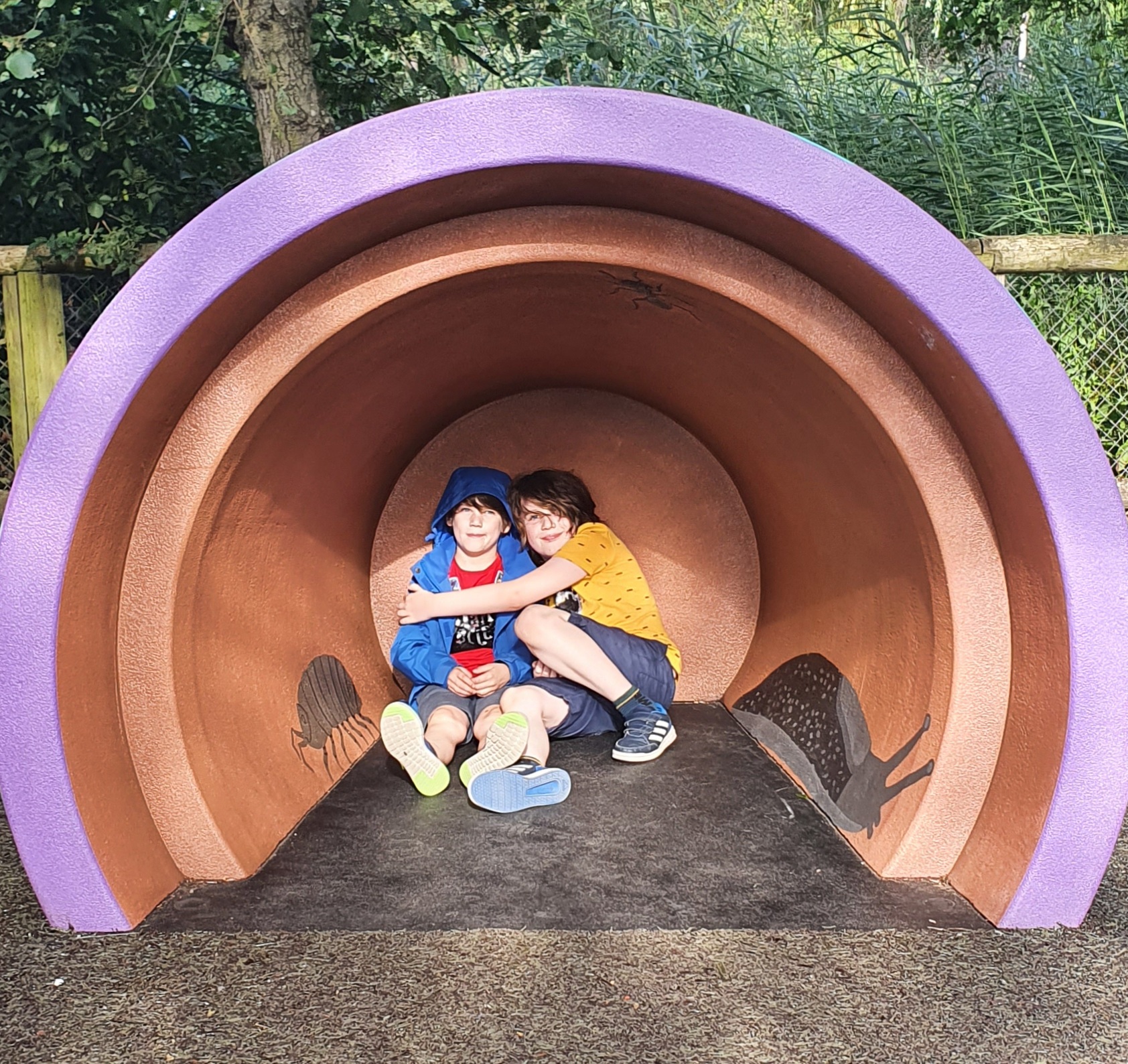 Two boys hugging in what looks like an upturned giant plant pot at Chester Zoo