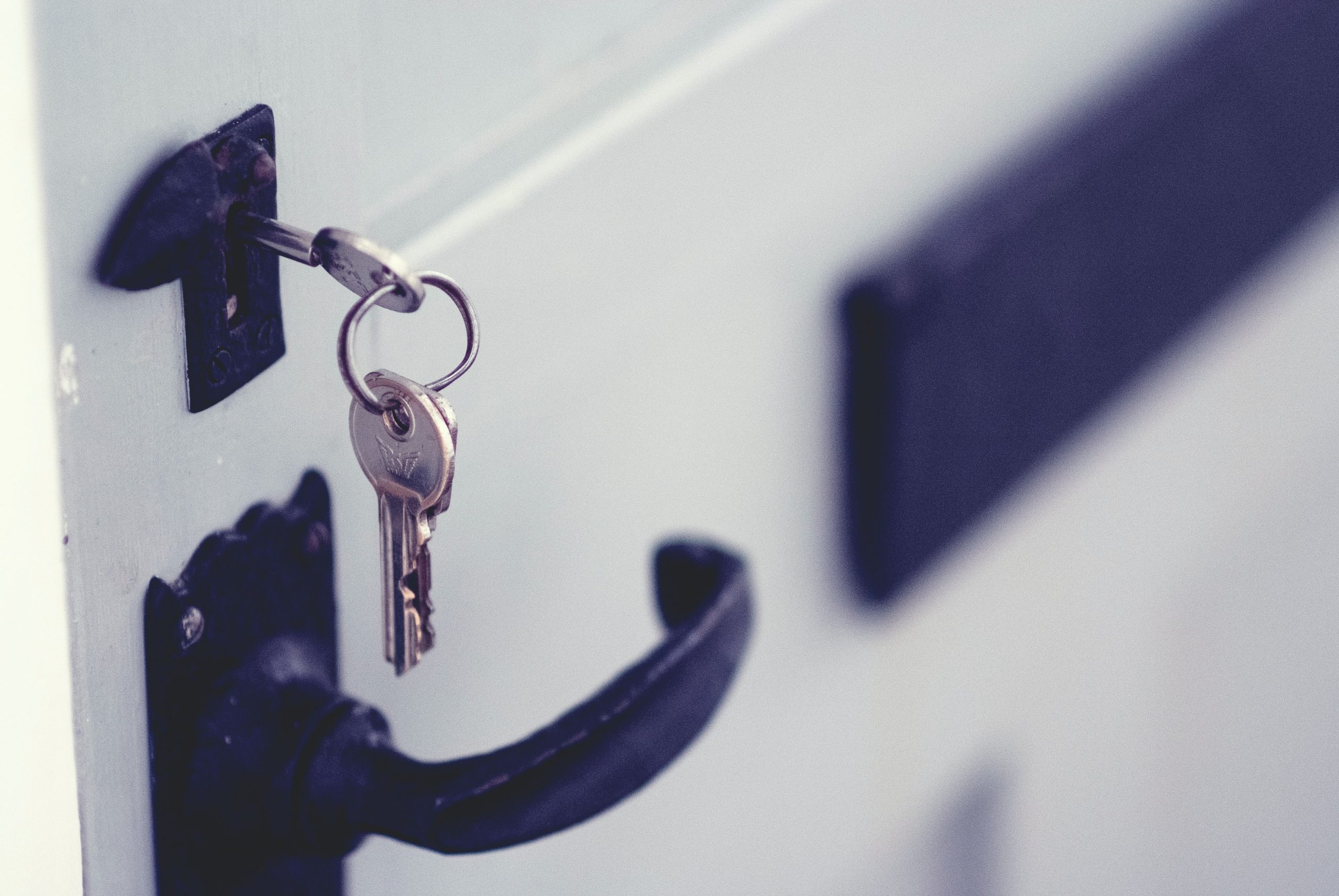 a white door with a key in the lock, and a black handle and letterbox; 4 Effective Ways to Secure and Protect Your Home