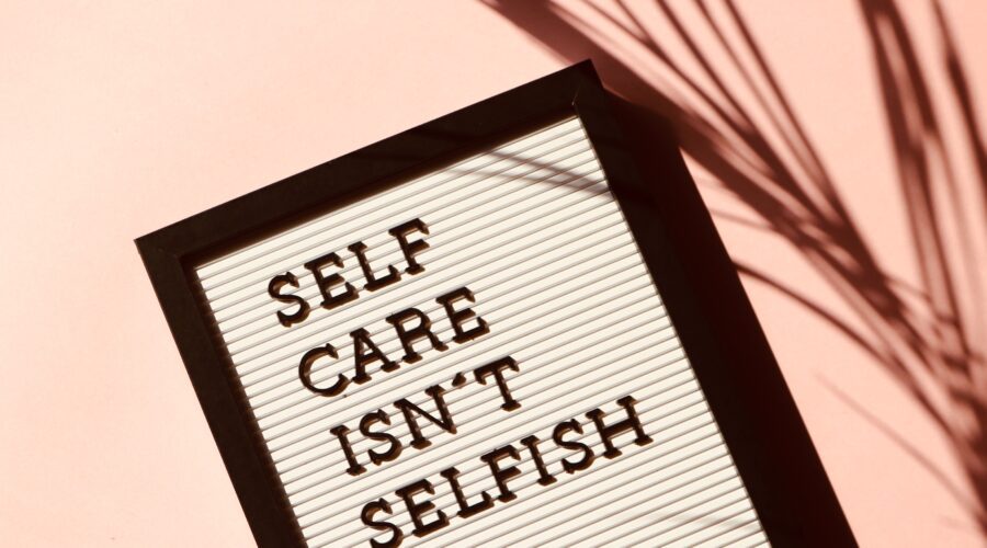 The image shows a message board laid flat saying "self care isn't selfish"