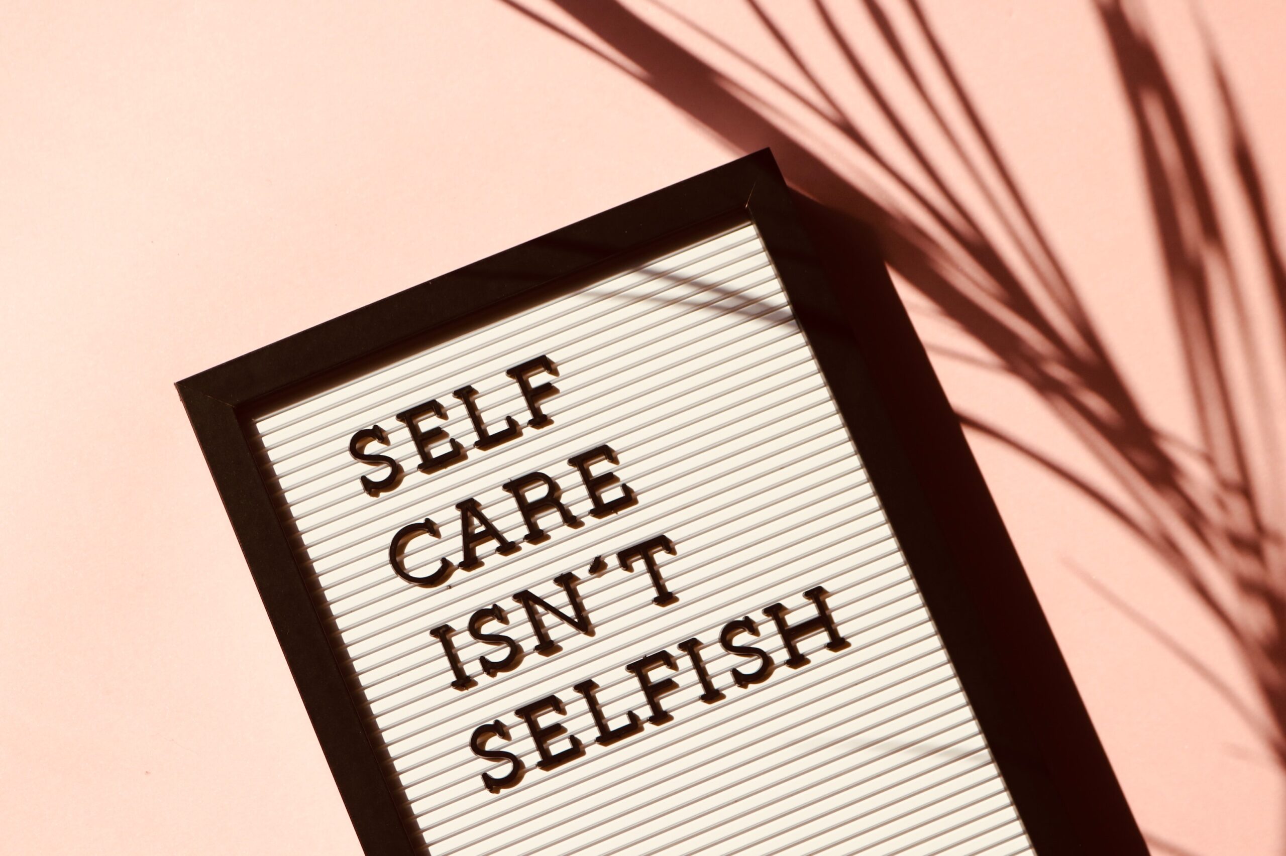 The image shows a message board laid flat saying "self care isn't selfish"
