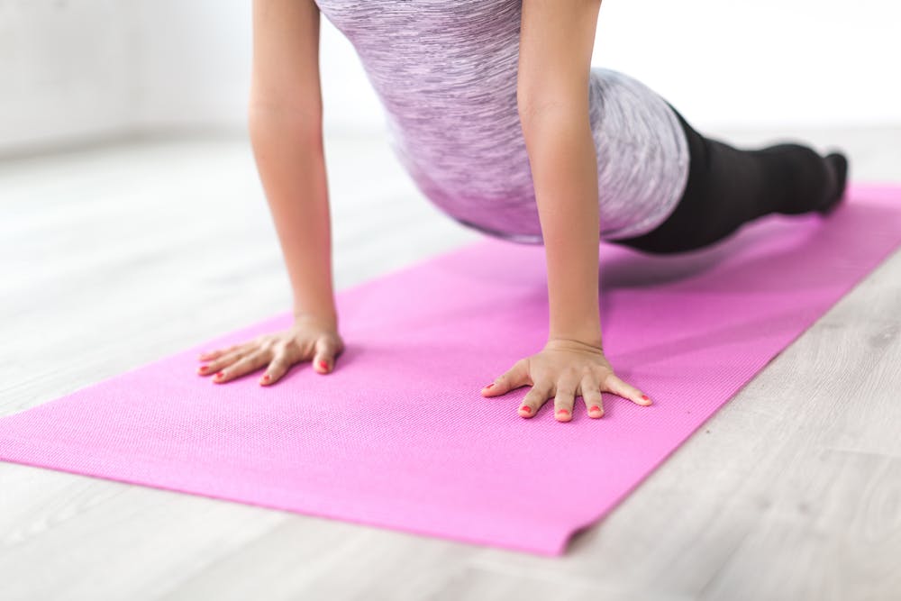 a woman doing a yoga pose on a pink yoga mat