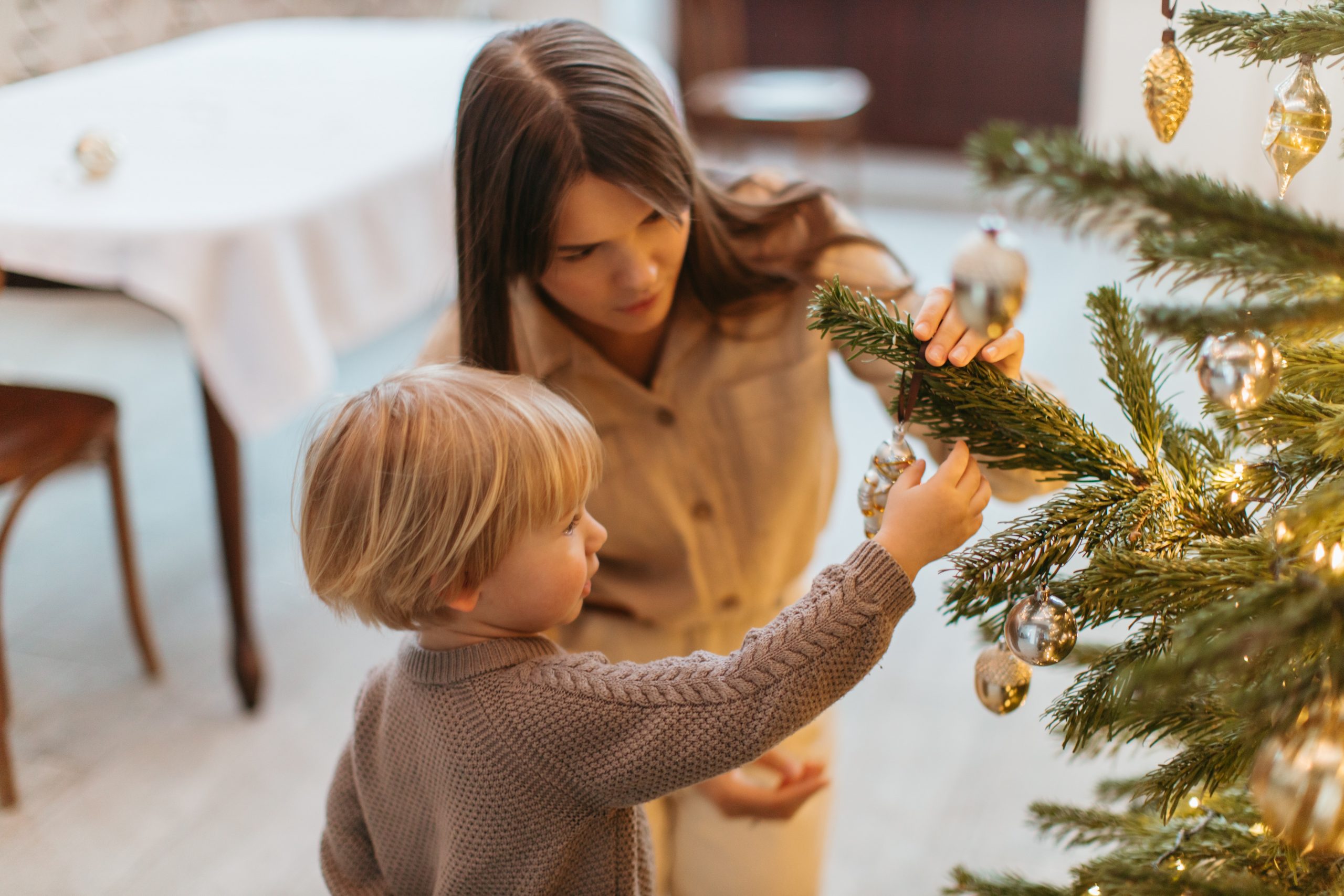 a woman and boy decorating a christmas tree