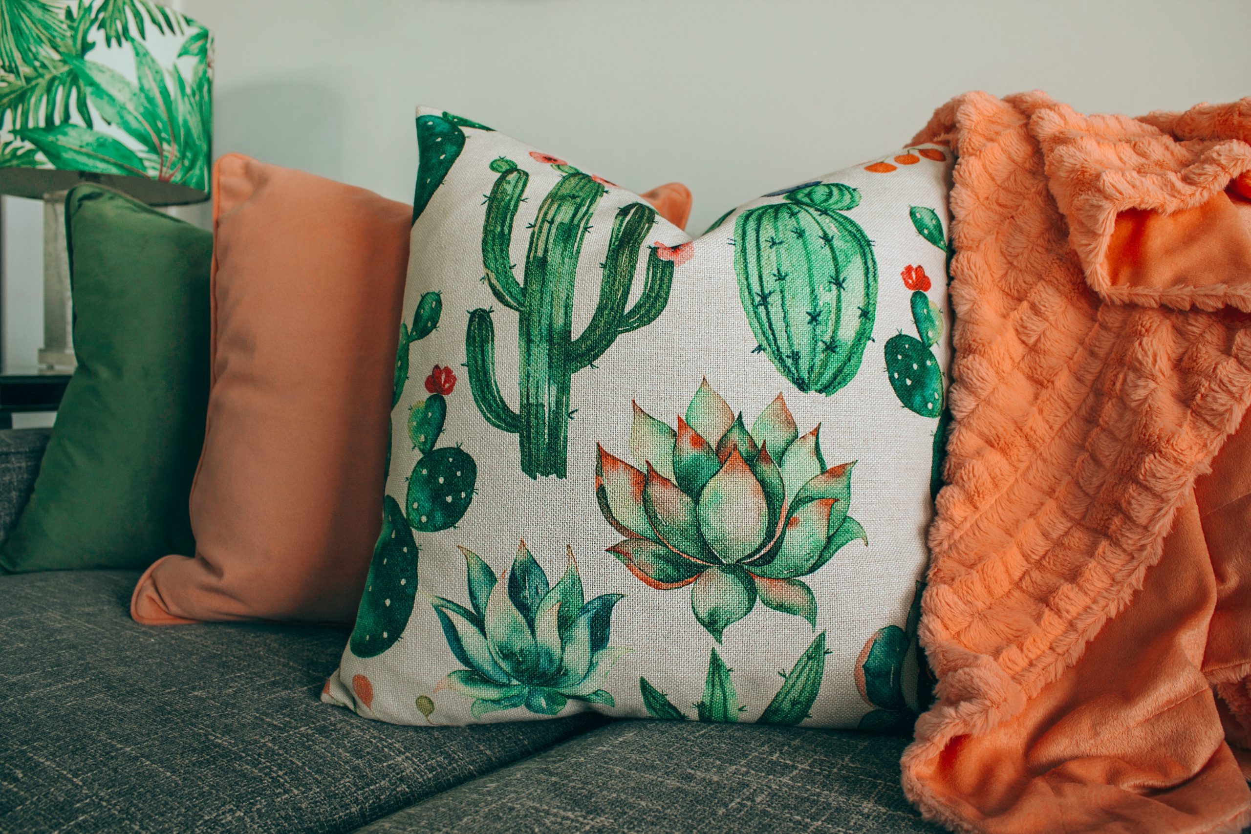 four orange and green cushions, the prominent one has cactus images printed all over it