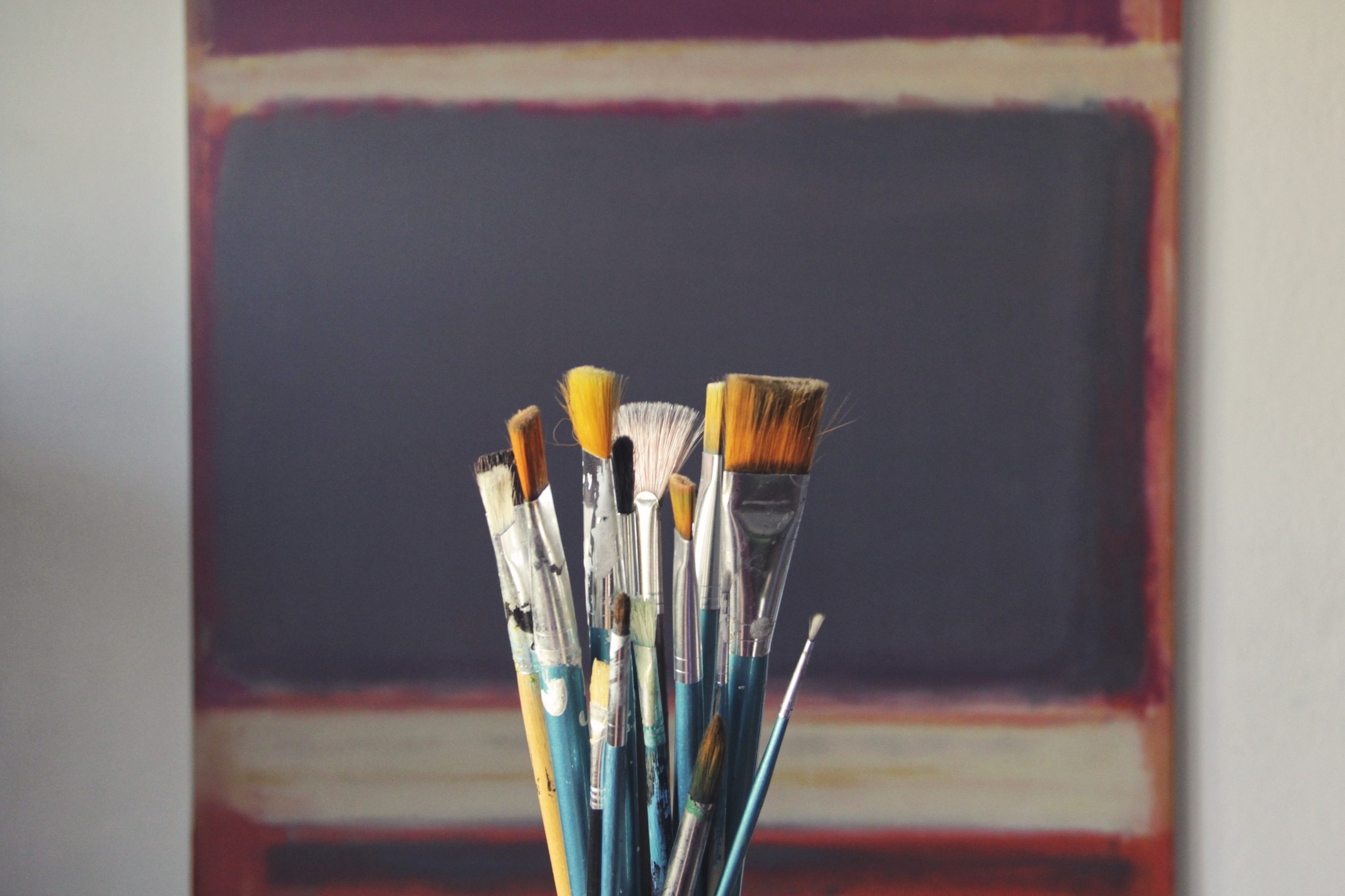 a collection of artistic paintbrushes stood upright in a pot