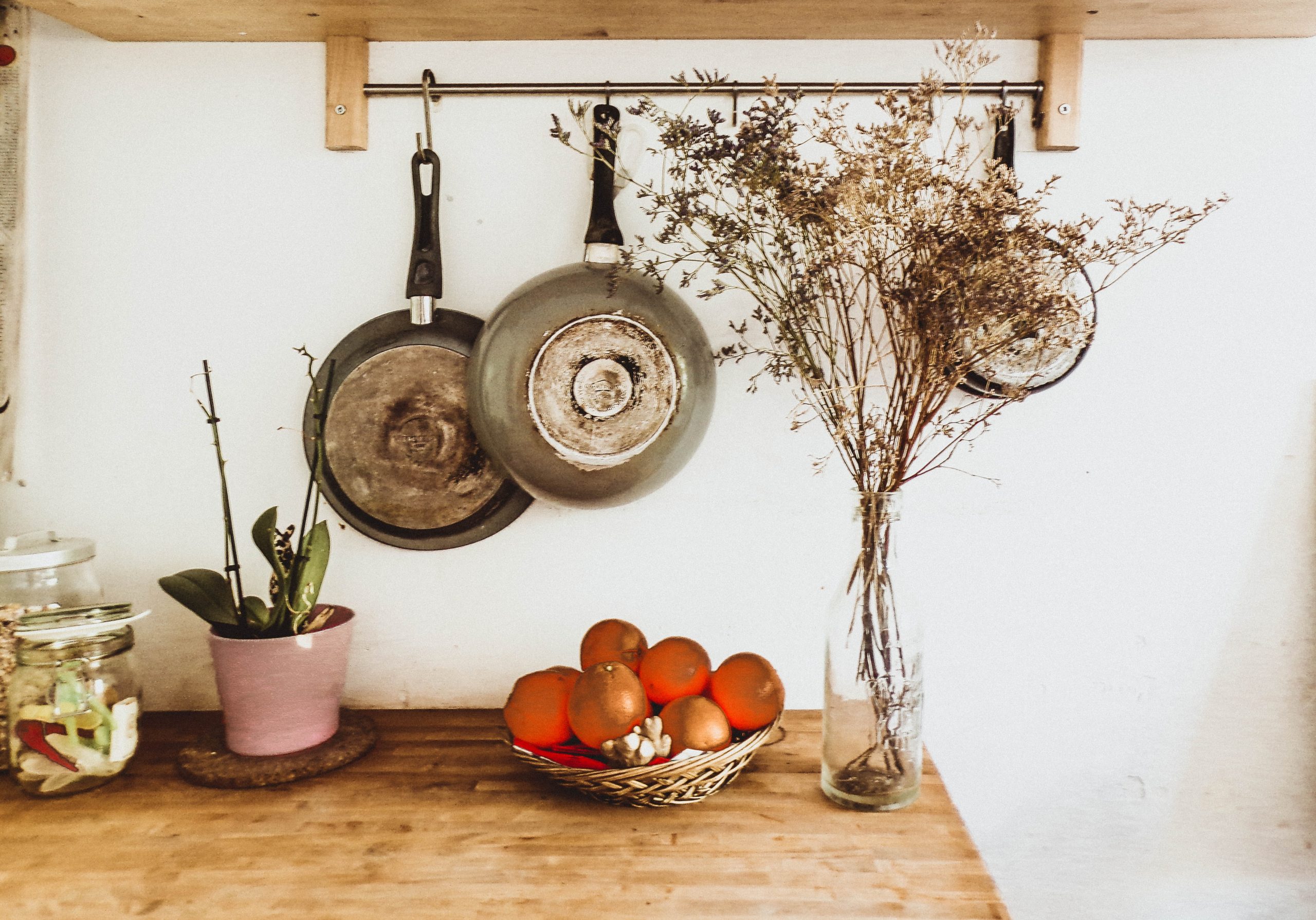 two pans hanging on the wall above a wooden surface, holding pots of various items; Finishing Touches for Your Home Design
