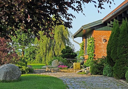 landscaped garden with brick house in the background; How to Finally Tackle Your Neglected Garden