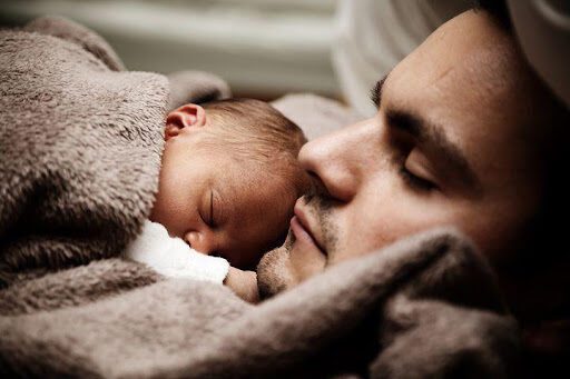 a man cuddling a baby underneath a blanket; What motivates people to sell their homes