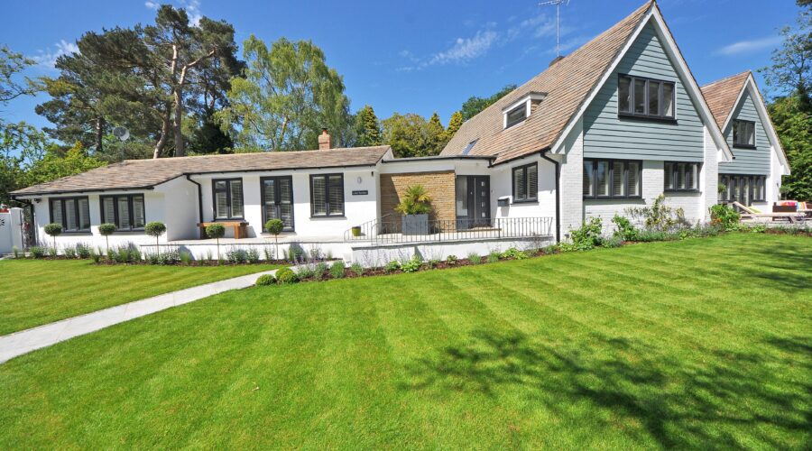 a large white house with a large green lawn in front and a large tree behind; Turn Your House Into A Home With These Tips