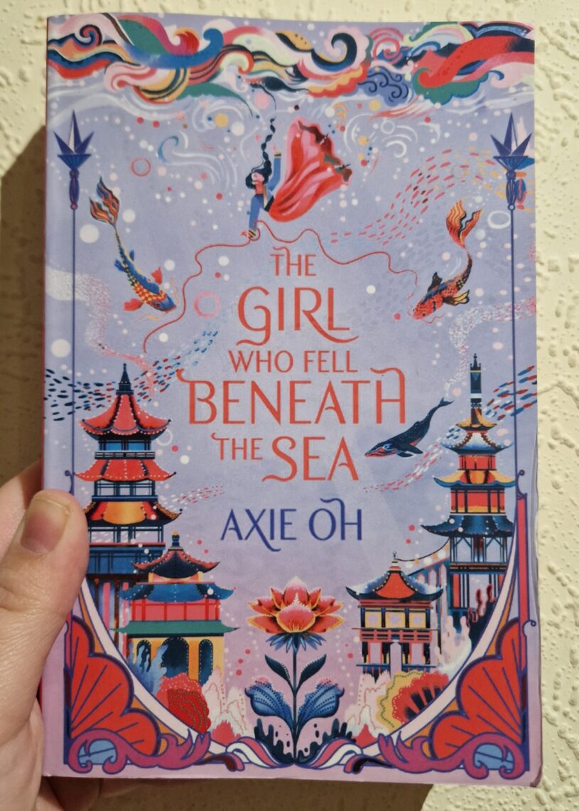A paperback copy of The Girl Who Fell Beneath The Sea