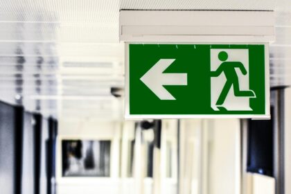 a corridor with a green safety sign - an arrow pointing right and a person running; Why You Can Never be Too Safety Conscious in Business