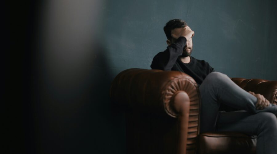 A man holding his head in his hands while sitting on a sofa; How to Mentally Recover After a Motorcycle Accident