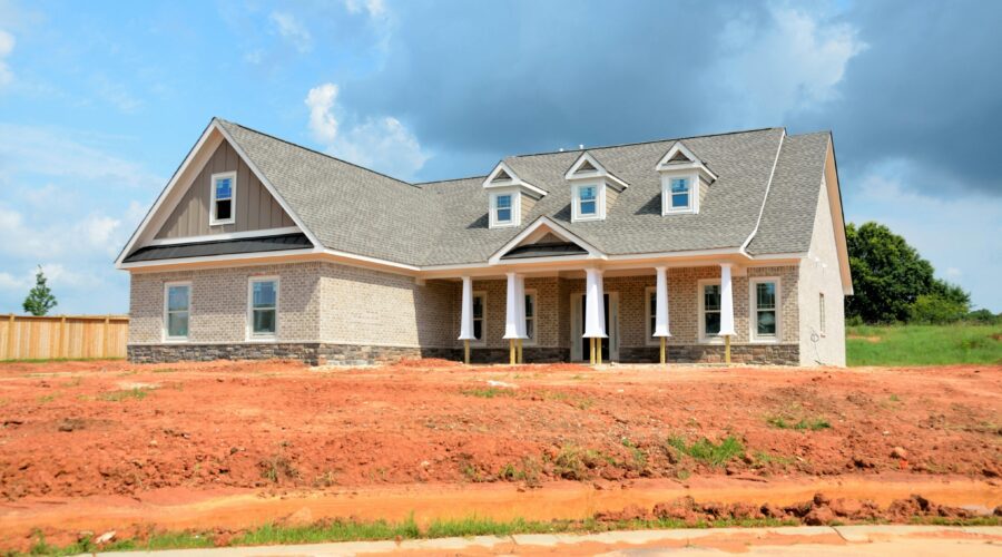 An L shaped house in the distance with orange dusty dirt in front of it; Planning To Build Your Dream Home Here's What You Need To Remember