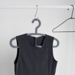 The photo shows a plain black sleeveless dress on a black hanger against a white background; Dressing Up as Self-Care The Power of Looking Good to Feel Great