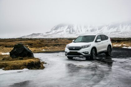 A large white family car stood still on a wet surface with snowy mountains in the background; How to Ensure a Car is Safe for Your Family