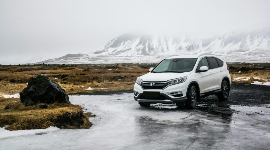A large white family car stood still on a wet surface with snowy mountains in the background; How to Ensure a Car is Safe for Your Family