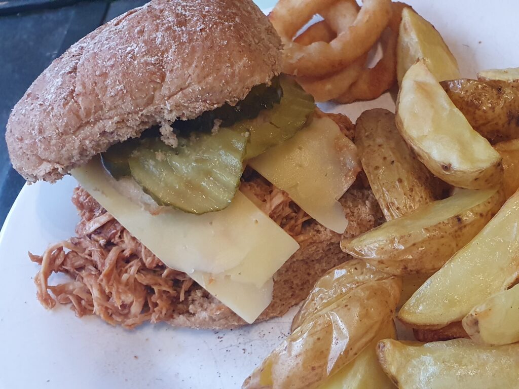 BBQ pulled pork served in a roll with potato wedges